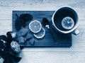 A flat lay on the classic blue background, a cup of tea with slices of lemon, spoon, mint leaves and a rose flower, morning tea Royalty Free Stock Photo