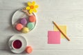 Flat lay. Close up. Bright colorful french macarons, yellow felt flower, a cup of berry tea, a pencil, stickers. Copy space