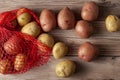 Flat lay  close up image featuring a red mesh potato sack with pink and yellow raw organic potatoes Royalty Free Stock Photo