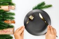 flat lay close-up on top of woman hands holding knife and fork over empty black plate on white isolated background with Royalty Free Stock Photo