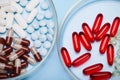 Flat lay. Close-up of various pills and gel capsules in petri dish over blue background. Pharma business and industry