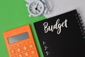 Flat lay closeup of an alarm clock, calculator, and notebook with editable text - BUDGET