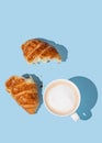 Flat lay of coffee cup and fresh broken croissant on blue background with shadow Royalty Free Stock Photo