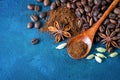 Flat lay. Coffee grains scattered on a blue textural background, anise stars, cardamom and ground coffee in a wooden spoon. Top Royalty Free Stock Photo