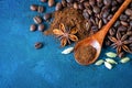 Flat lay. Coffee grains scattered on a blue textural background, anise stars, cardamom and ground coffee in a wooden spoon. Top