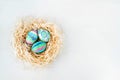 Flat lay of colorful Easter eggs in nest. Easter eggs colored with blue and green paint in various patterns.