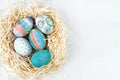 Flat lay of colorful Easter eggs in nest. Group of Easter eggs on white background
