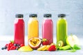 Flat-lay of colorful smoothies in bottles with tropical fruit and superfoods on concrete background Royalty Free Stock Photo