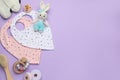 Flat lay composition with baby accessories and bibs on violet background, space for text