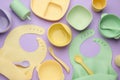Flat lay composition with baby feeding accessories and bibs on violet background