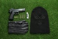 Flat lay composition with balaclava and weapons on green grass Royalty Free Stock Photo
