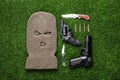 Flat lay composition with balaclava and weapons on green grass Royalty Free Stock Photo