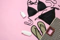 Flat lay composition with black swimsuit and beach accessories on pink background. Royalty Free Stock Photo