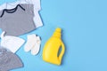 Flat lay composition with bottle of detergent and children`s clothes on light blue background Royalty Free Stock Photo