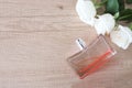 Flat lay composition with bottle of perfume and roses on wooden background, space for text. White roses, pink perfume bottle Royalty Free Stock Photo