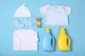 Flat lay composition with bottles of detergent and children`s clothes on light blue background Royalty Free Stock Photo