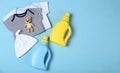 Flat lay composition with bottles of detergent and children`s clothes on light blue background. Space for text Royalty Free Stock Photo