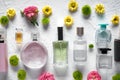 Flat lay composition with bottles of perfume and flowers on white textured background