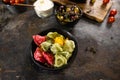 Flat lay composition of bowl of dumplings, jar of sour cream on wooden board