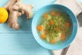 Flat lay composition with bowl of fresh homemade soup to cure flu on wooden background