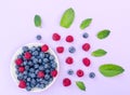 Flat lay composition of bowl with raspberries and blueberries and plenty of different berries and fresh green mint leaves as a