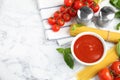 Flat lay composition with bowl of sauce, pasta and tomatoes on marble table Royalty Free Stock Photo