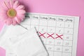 Flat lay composition with calendar, menstrual pads and gerbera flower on color background.