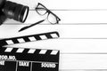 Flat lay composition with camera and movie clapper on white wooden table, space for text. Video production industry Royalty Free Stock Photo