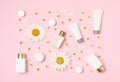 Composition with chamomiles and cosmetic products on pink background