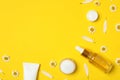 Composition with chamomiles and cosmetic products on yellow background. Space for text