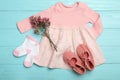 Flat lay composition with child`s clothes and flowers on blue wooden table Royalty Free Stock Photo