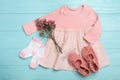 Flat lay composition with child`s clothes and flowers on blue wooden table Royalty Free Stock Photo