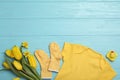 Flat lay composition with child`s clothes and flowers on blue wooden table. Space for text Royalty Free Stock Photo