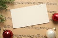 Flat lay composition with Christmas decorations and blank card on music sheets Royalty Free Stock Photo