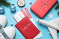 Flat lay composition with Christmas decorations, passport and airline tickets on light blue background. Winter vacation Royalty Free Stock Photo