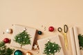 Flat lay composition with Christmas gifts decorated fir branches, scissors, wrapping paper, baubles on beige table