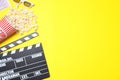 Flat lay composition with clapperboard and popcorn on yellow background, space for text Royalty Free Stock Photo