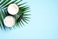 Flat lay composition with coconut oil on blue background. Top view half coconut, sliced coconut in bowl, essential oil bottle,