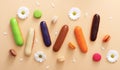 Flat lay composition of colorful french macaroons,eclairs,white flowers and petals on beige background. Almond cookies.Top view.