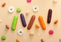 Flat lay composition of colorful french macaroons,eclairs,white flowers and petals on beige background. Almond cookies.Top view.