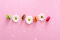 Flat lay composition of colorful french macaroons,white flowers and petals on pink background. Almond cookies.Top view. Valentine