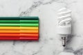 Flat lay composition with colorful markers and fluorescent light bulb on white marble background