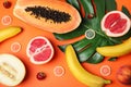 Flat lay composition with condoms and exotic fruits on orange background.