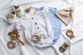 Flat lay composition with baby clothes and accessories on white bedsheet