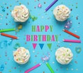 Flat lay composition with cupcakes and text Happy Birthday on light blue background Royalty Free Stock Photo