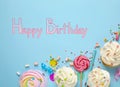 Flat lay composition with delicious cupcakes and text Happy Birthday on blue background Royalty Free Stock Photo