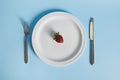 Flat lay composition with a delicious strawberry on a plate, fork and knife isolated on blue background Royalty Free Stock Photo