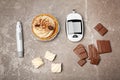 Flat lay composition with digital glucometer and sweets on color background. Diabetes concept