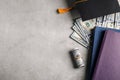 Flat lay composition with dollars and student graduation hat on stone background. Tuition fees concept