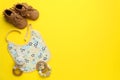 Flat lay composition with drool baby bib and accessories on yellow background. Space for text